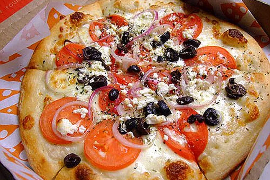 Greek pizza with feta, tomatoes and olives — representative food photograph