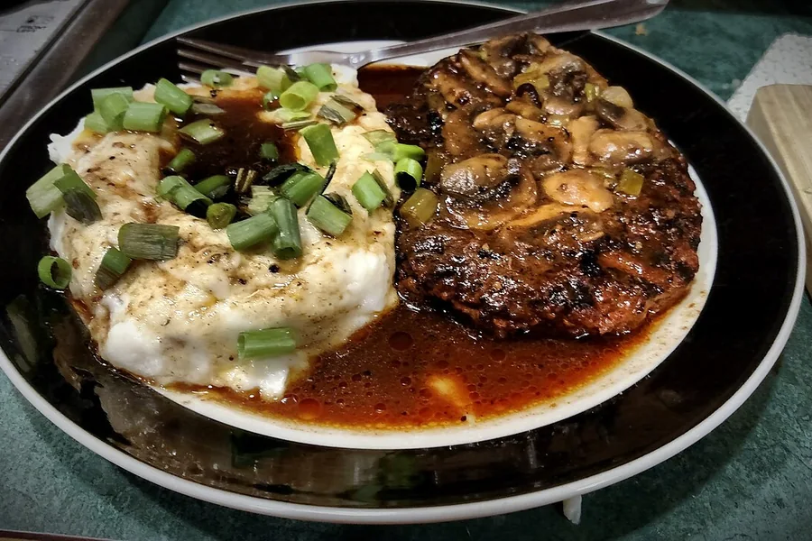 Smothered steak with mushrooms and mashed potatoes — representative food photograph